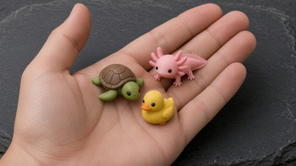 Three tiny printed critters - sea turtle, axolotl and duckling - in an open hand (AI-generated preview)